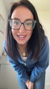 Woman in blue zip-up jacket and glasses.