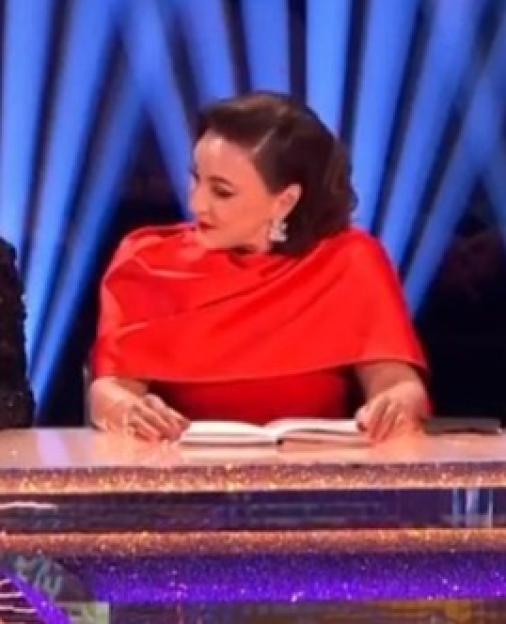 Five judges on a sparkling desk, with blue lights in the background.