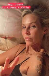 Woman in bed giving peace sign.