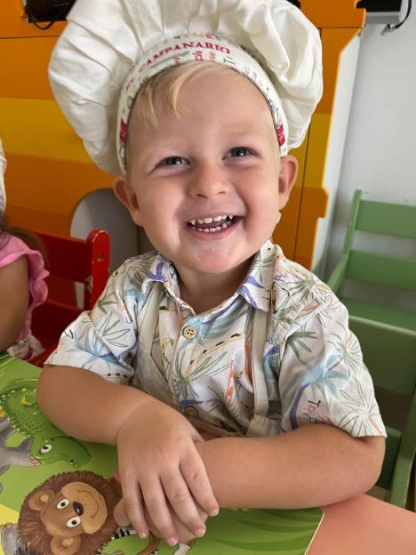 Smiling toddler wearing a chef's hat.