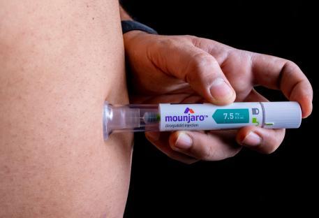 Person injecting Mounjaro pen.