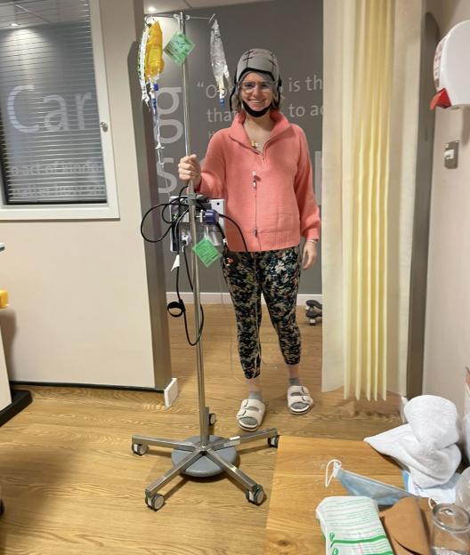 Woman in hospital room with IV stand.
