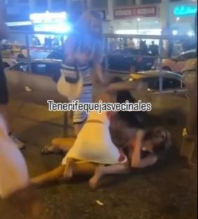 Two women fighting on the ground at night.