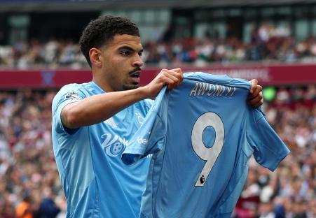 Morgan Gibbs-White holding up Taiwo Awoniyi's jersey.