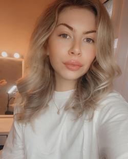 Woman with blonde hair wearing a white shirt and necklace.