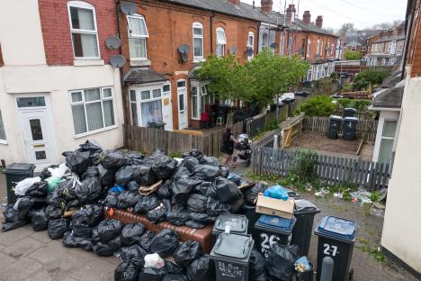 A large pile of garbage bags and waste blocking a residential street during a refuse workers' strike.