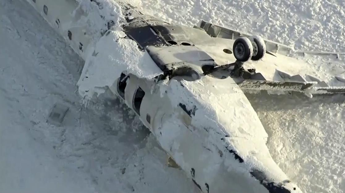 Aerial view of an overturned plane covered in snow at Toronto Pearson Airport.