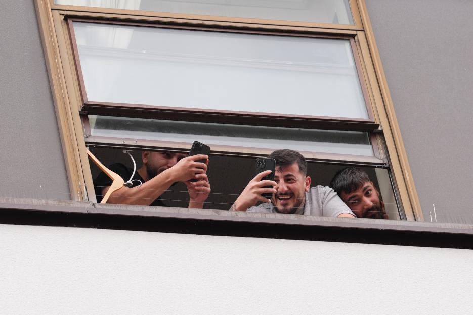 Hotel residents look out a window at a protest below.