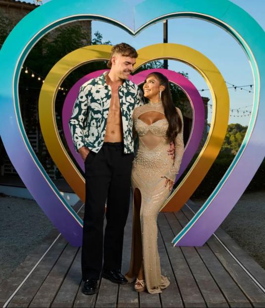 Couple posing in front of heart-shaped archway.