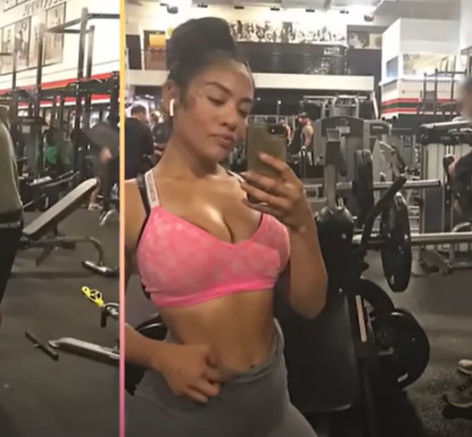 A woman in a pink sports bra takes a selfie in a gym.