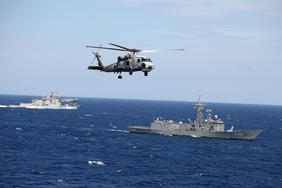 A Turkish Navy Seahawk helicopter flies over the Adriatic Sea with US Navy ships in the background during NATO's Neptune Strike 25.3 exercise.