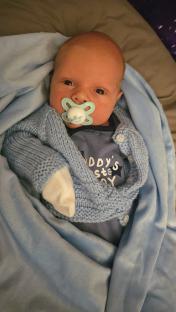 Baby Harley Wilkinson in a blue knitted cardigan.