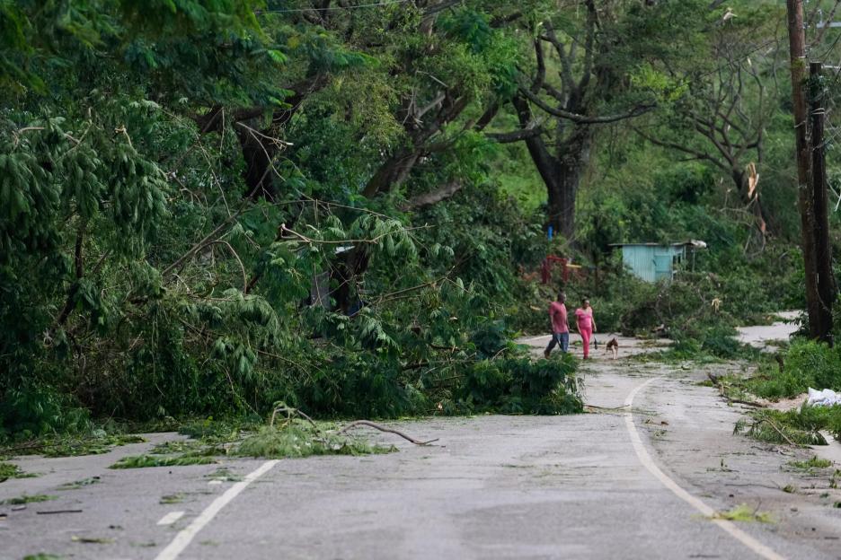 People walk along a road covered in hurricane debris after Hurricane Melissa in Spurr Tree, Jamaica.