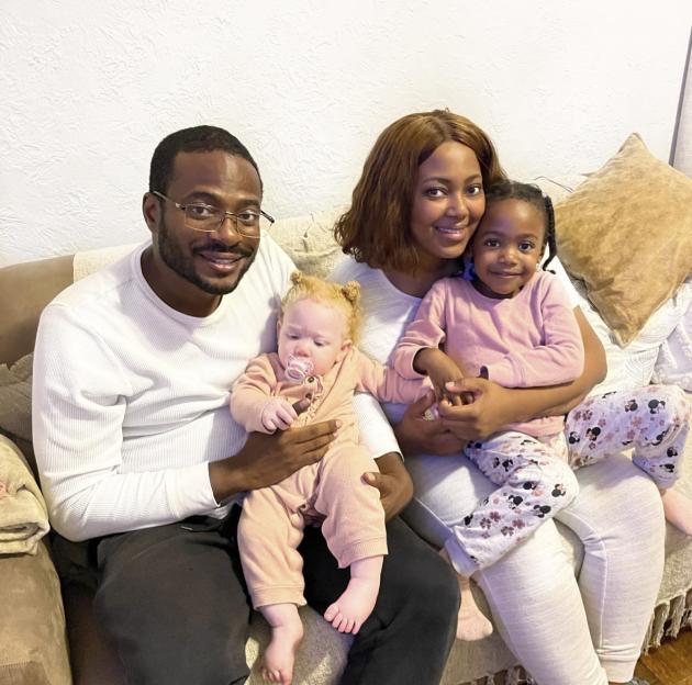 Family portrait of a Black couple and their three children; one child has albinism.