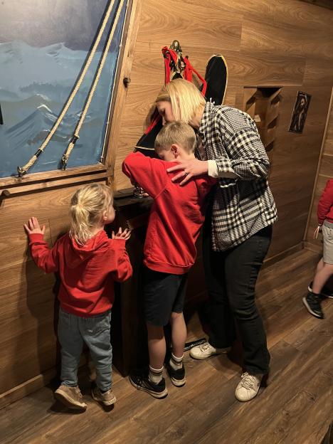 A woman and two children looking at something in a pirate-themed room.