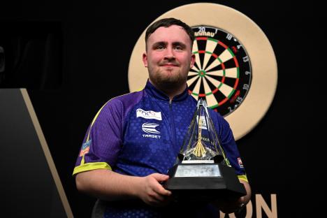Luke Littler holding a darts trophy.