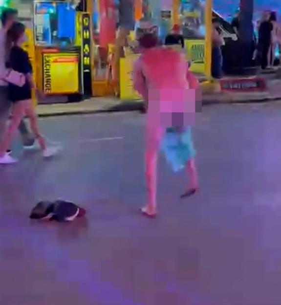 A man dancing naked with blurred genitalia in the middle of a street at night.
