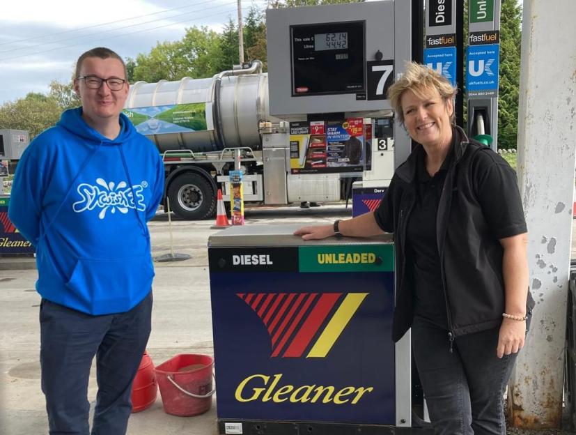 Rich James Cross and a woman pose in front of a Gleaner fuel pump.