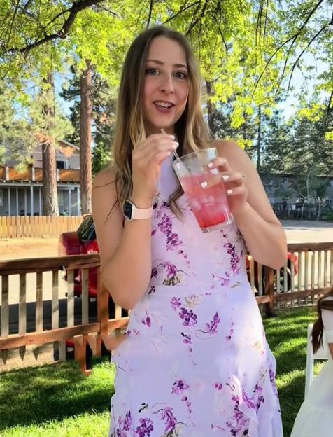 Woman in floral dress holding a pink drink.