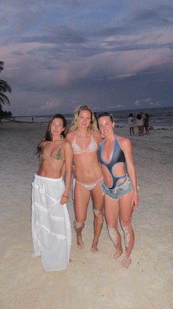 Three women on a beach at dusk.