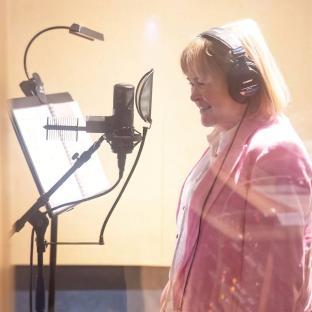 Susan Boyle singing into a microphone in a recording studio.