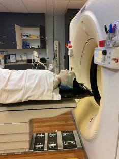 A patient undergoing radiation treatment with a mask fitted to their head.