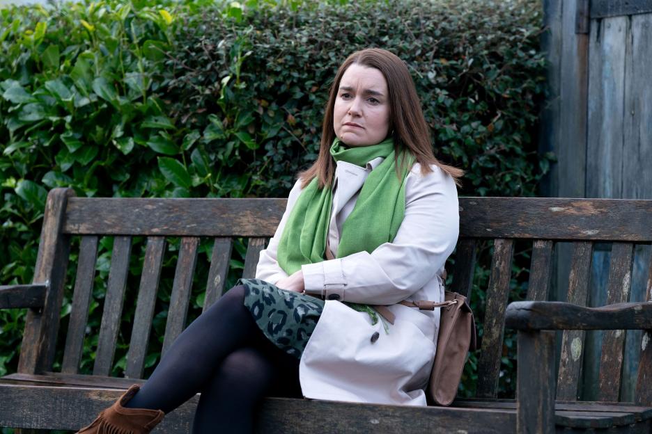 Vicki Fowler, from EastEnders, sitting on a park bench.