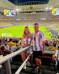 Couple in Argentina jerseys at a soccer game.