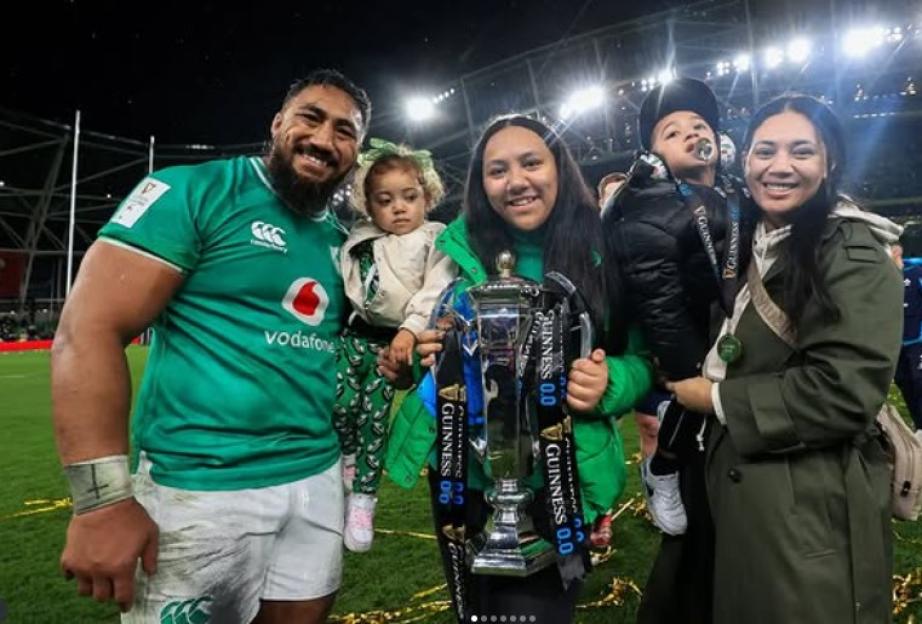 Bundee Aki and his family holding a rugby trophy.