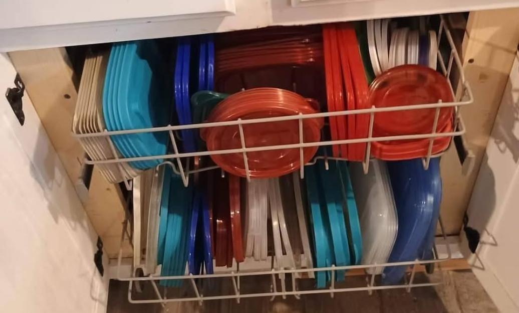 Organized plastic food storage containers and lids in a kitchen cabinet.