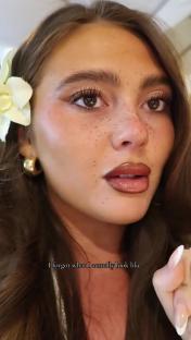 Close-up of a woman's face with freckles and makeup.
