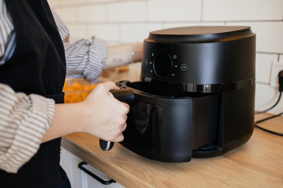 Woman using an air fryer to cook food.