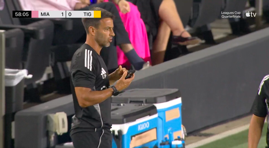 Screenshot of a soccer coach looking at his phone during a Leagues Cup quarterfinal.