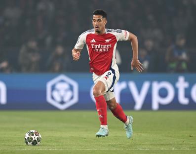 William Saliba of Arsenal running with the ball during a soccer match.