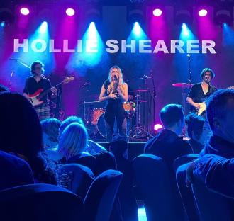 Hollie Shearer performing on stage with her band.