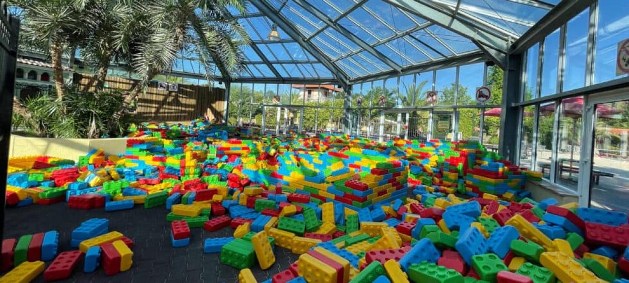 A room filled with colorful oversized plastic building blocks beneath a glass ceiling.