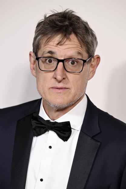 Louis Theroux wearing a black tuxedo and bow tie, with glasses.