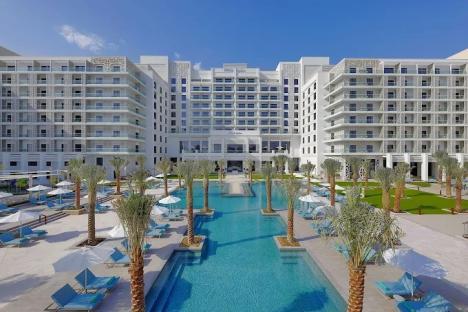 Hilton Abu Dhabi Yas Island hotel with pool and palm trees.