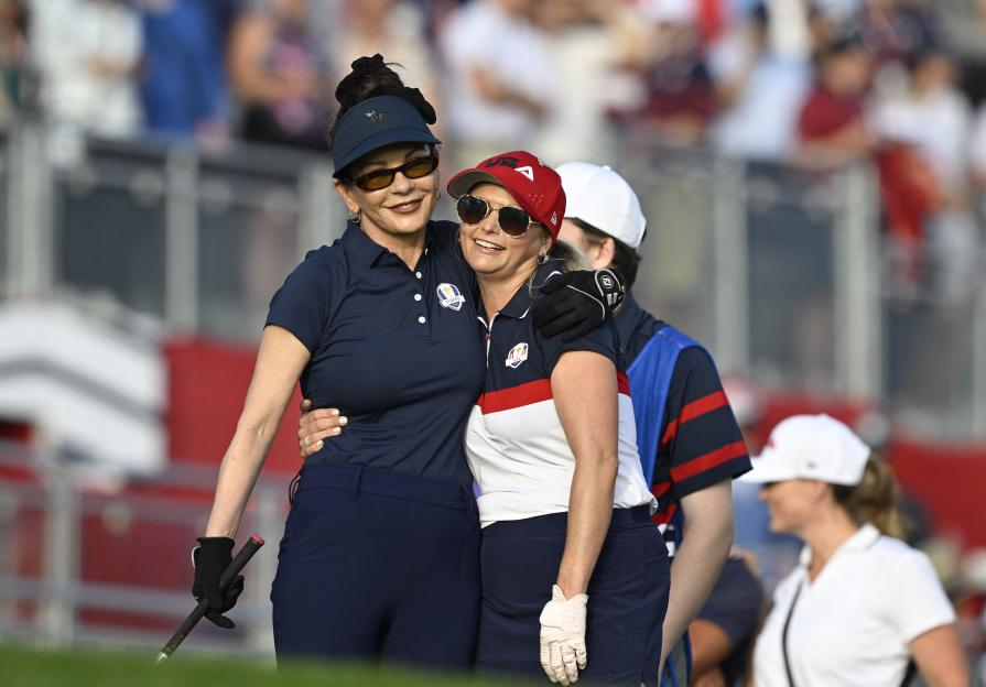 Catherine Zeta-Jones and Miranda Lambert embrace during a celebrity match at the 2025 Ryder Cup.