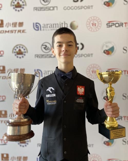 Young snooker player holding two trophies.