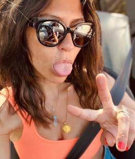 Woman sticking out tongue and giving peace sign.