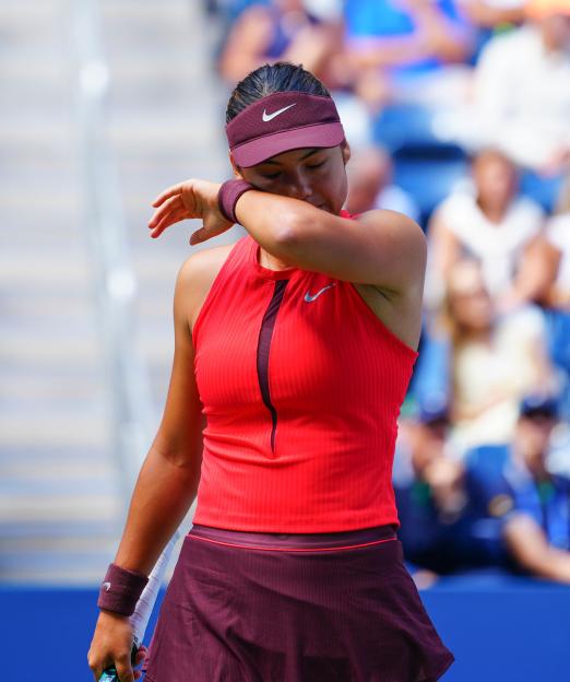 Emma Raducanu wiping sweat during a tennis match.