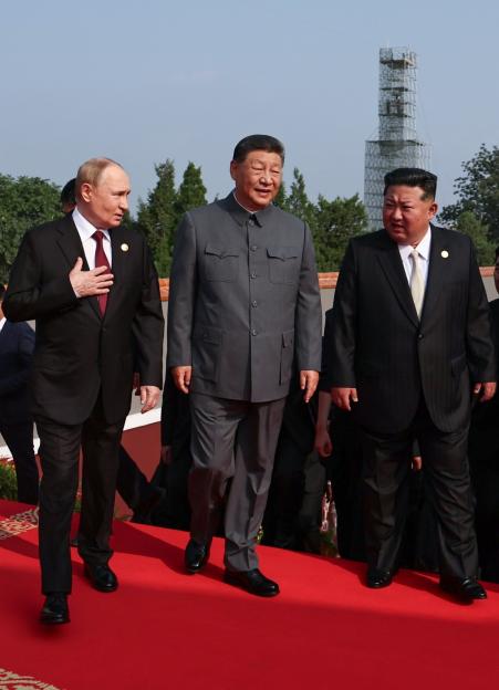 Putin, Xi Jinping, and Kim Jong Un walking on a red carpet.
