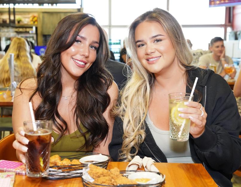 Two women at a pub, enjoying drinks and appetizers.