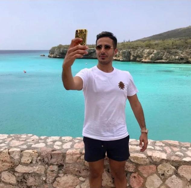 Man taking a selfie by a turquoise ocean.