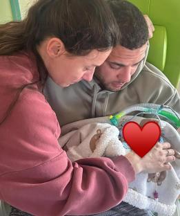 Parents holding their baby in a hospital bed.