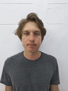 Portrait of a young man with blond hair wearing a gray t-shirt.