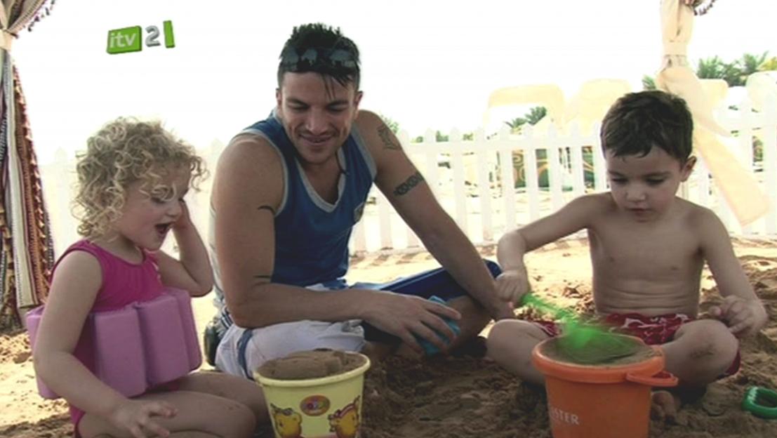 Peter Andre building sandcastles with his children on a beach.