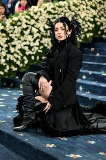 Charli XCX at the Met Gala in a black feathered outfit.