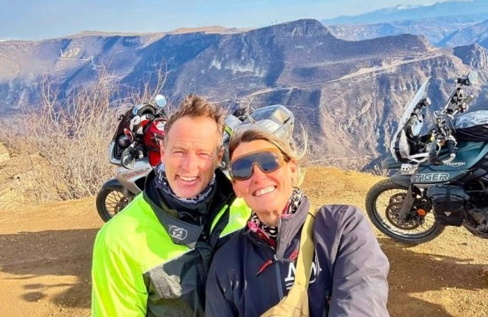 Couple on motorcycles overlooking a mountain valley.